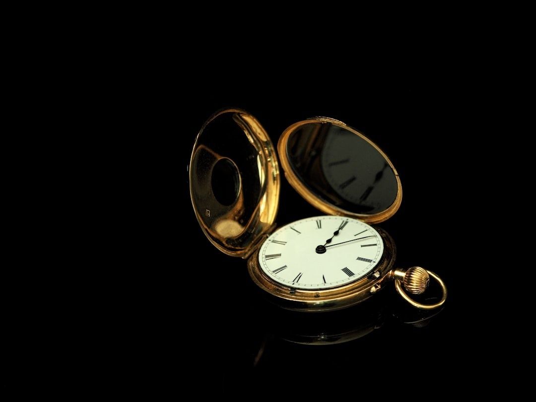 Opengeklapt gouden zakhorloge met wijzerplaat op een zwarte ondergrond